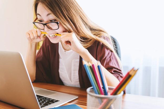 meisje kijkt naar haar computer en bijt op het potlood